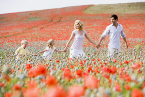 Family walking in poppy field holding hands smiling